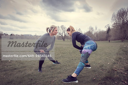 Women in field in lunge pose stretching