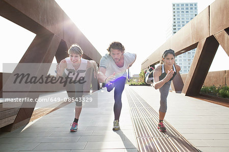 Man and two women training on one leg on urban footbridge