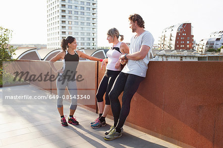 Two women and man training, chatting on urban footbridge