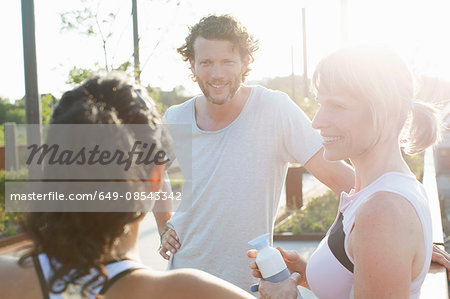 Two women and man training, chatting in sunlight
