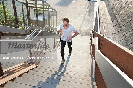 Male runner running up urban stairway