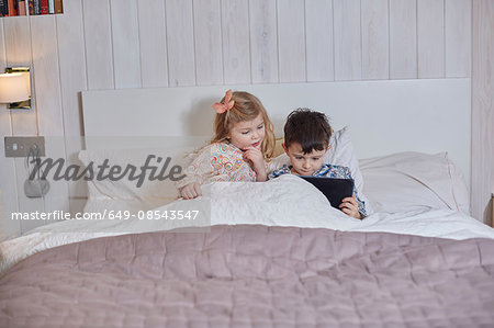 Children using digital tablet in bed