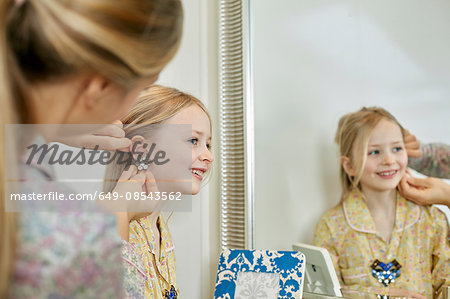 Mother and daughter playing dress-up in bedroom