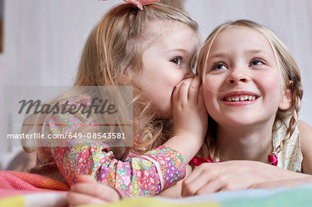 Girl whispering into sister's ear