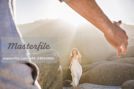 View though mans arms of woman wearing white dress running to him