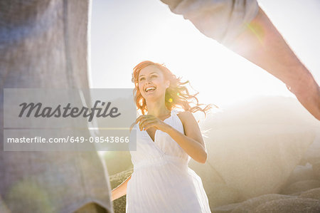 View though mans arms of woman wearing white dress running to him