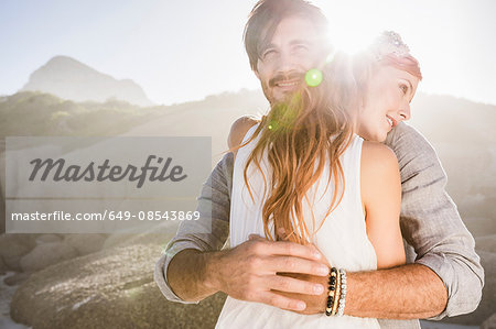 Man hugging red haired woman in front of rocks smiling