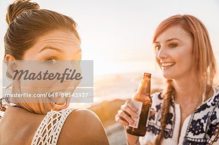 Portrait of two mid adult female friends pulling faces on beach at sunset, Cape Town, South Africa Portrait of two mid adult female friends pulling faces on beach at sunset, Cape Town, South Africa
