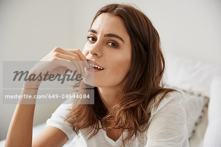 Portrait of beautiful young woman sitting on bed