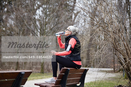 Mature woman training in park, drinking bottled water