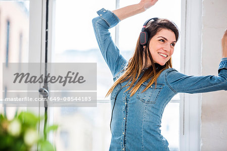 Young woman dancing in front of city apartment window