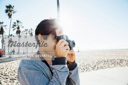 Young man, outdoors, using digital camera