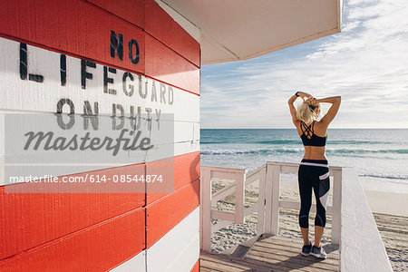 Young woman on lifeguard platform, looking at view, rear view
