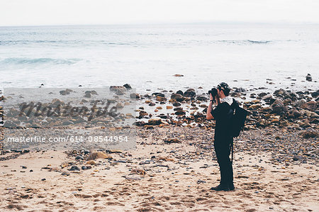 Male photographer photographing from beach, Crystal Cove State Park, Laguna Beach, California, USA