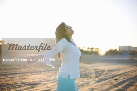 Woman with arms open on Santa Monica beach at sunset, Cresent City, California, USA