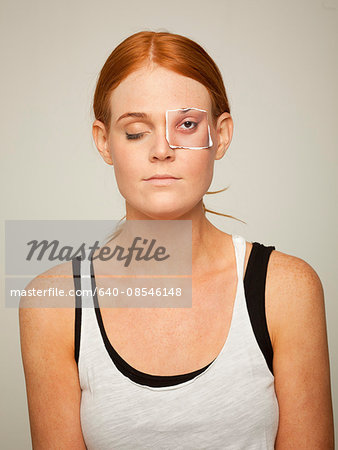 Studio shot of young woman wearing sleeveless top with artificial paper eye