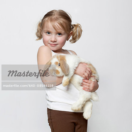 Studio shot of girl (2-3) holding rabbit