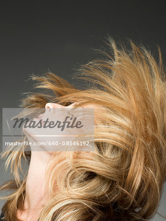 Blonde woman flipping hair in studio