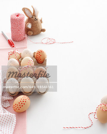 Carton of home decorated easter eggs and easter bunny on white table