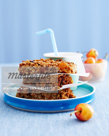Stack of muesli flapjacks, drink with bowl of cherries, kids lunch idea