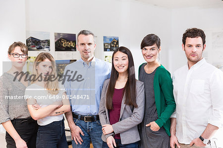 Colleagues side by side in office looking at camera smiling