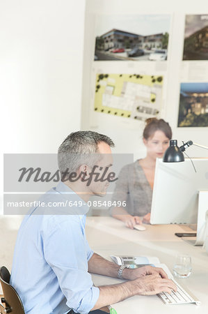 View through glass, side view of mature man in office using computer