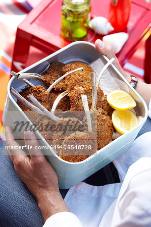 High angle view of mid adult man holding container of parmesan lamb cutlets