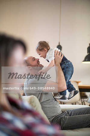 Father lifting up baby boy face to face smiling