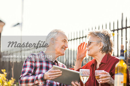 Senior couple on city rooftop garden using digital tablet