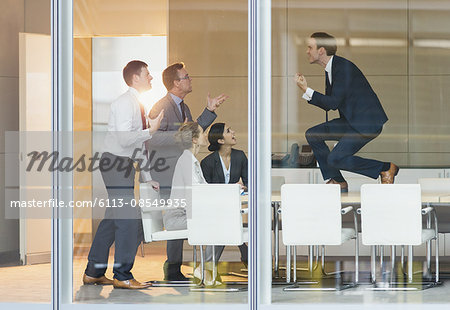 Exuberant businessman gesturing with fists on top of conference table Exuberant businessman gesturing with fists on top of conference table