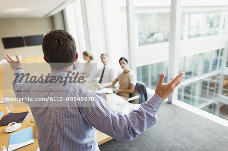 Businessman gesturing to colleagues in conference room meeting