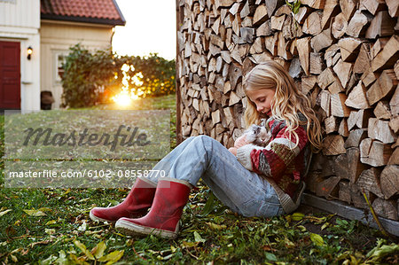 Girl sitting by log holding rabbit