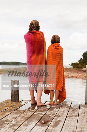 Two girls wrapped in towels standing on jetty