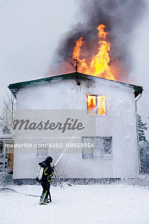 Fireman spraying water on burning building