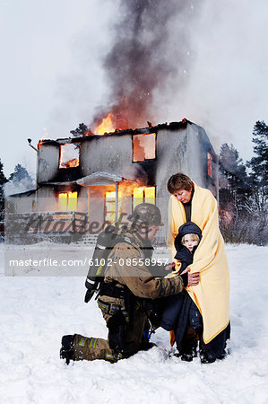 Fireman with rescued woman and girl in front of burning house