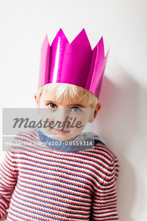 Portrait of boy wearing paper crown, studio shot
