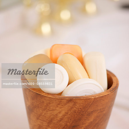 Variety of Bars of Soap in Wooden Bowl with Gold Sink Faucet in the Background