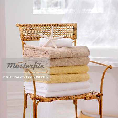 Stack of Fresh Towels and Starfish on Wicker Chair in Bathroom