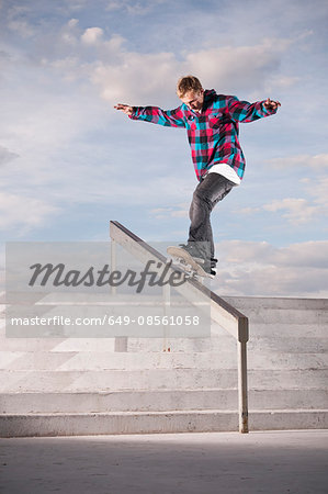 Skater sliding down rail on board