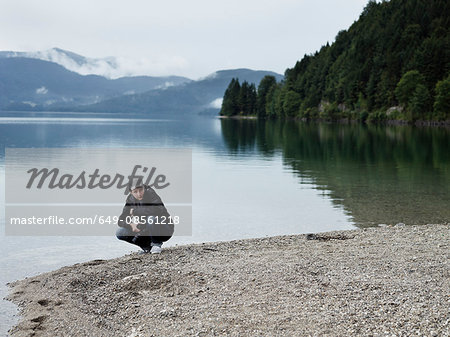 Hiker resting by still lake