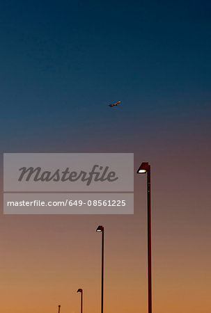 Airplane over street lights at dusk