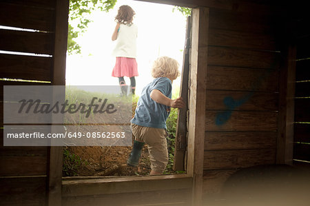 Boy and girl leaving through wooden window frame