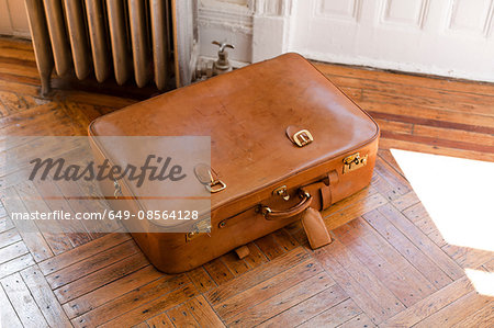 Brown leather suitcase on wooden floor