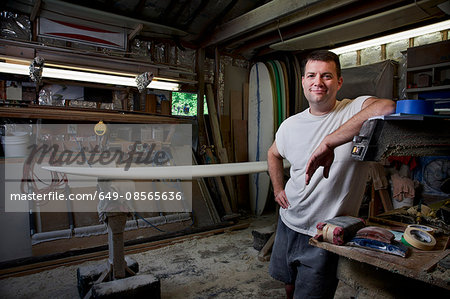 Portrait of mature man in his garage with surfboards