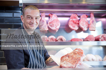 Portrait of butcher holding fresh meat in butchers shop