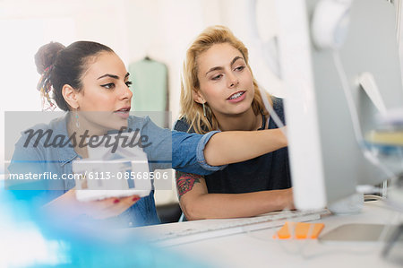 Female architects holding house model at computer in office