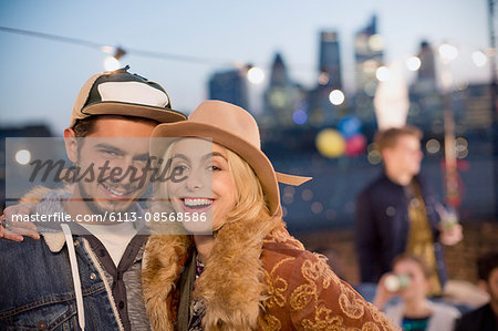 Portrait smiling young couple hugging at nighttime rooftop party