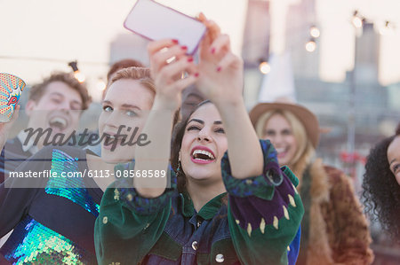 Young women laughing and taking selfie at rooftop party