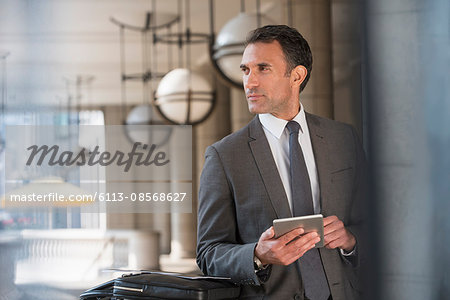 Corporate businessman with digital tablet looking away