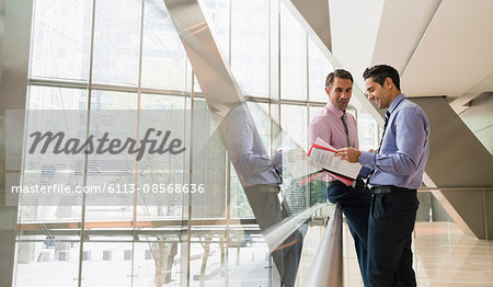 Corporate businessmen discussing paperwork in modern lobby